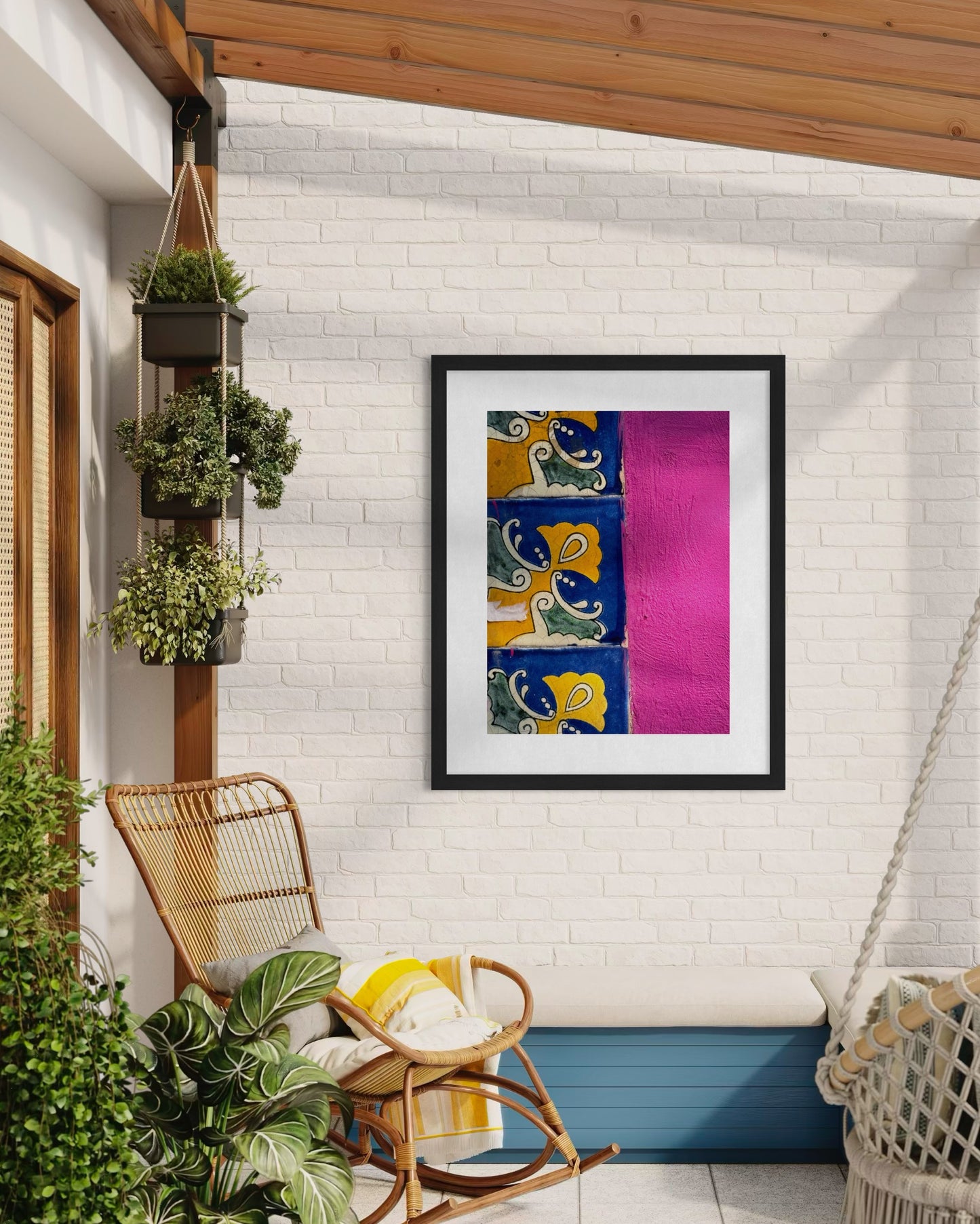 The "Vibrant Tiles and Bright Pink Wall - Fine Art Print" by Leslie Brashear Photography features a modern painting on a sunlit pink stucco patio in Puebla, Mexico, surrounded by plants, wicker chair, colorful tiles, and a cushioned bench.