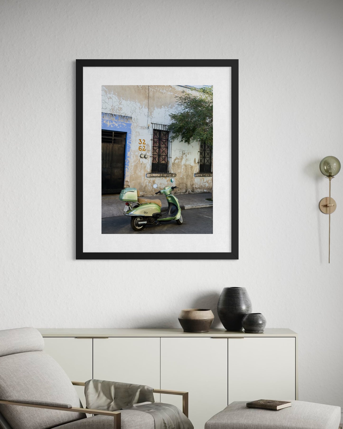 The "Weathered Facade and Vintage Scooter" fine art print by Leslie Brashear Photography adds vintage charm above a sideboard with decorative vases in a modern living room.