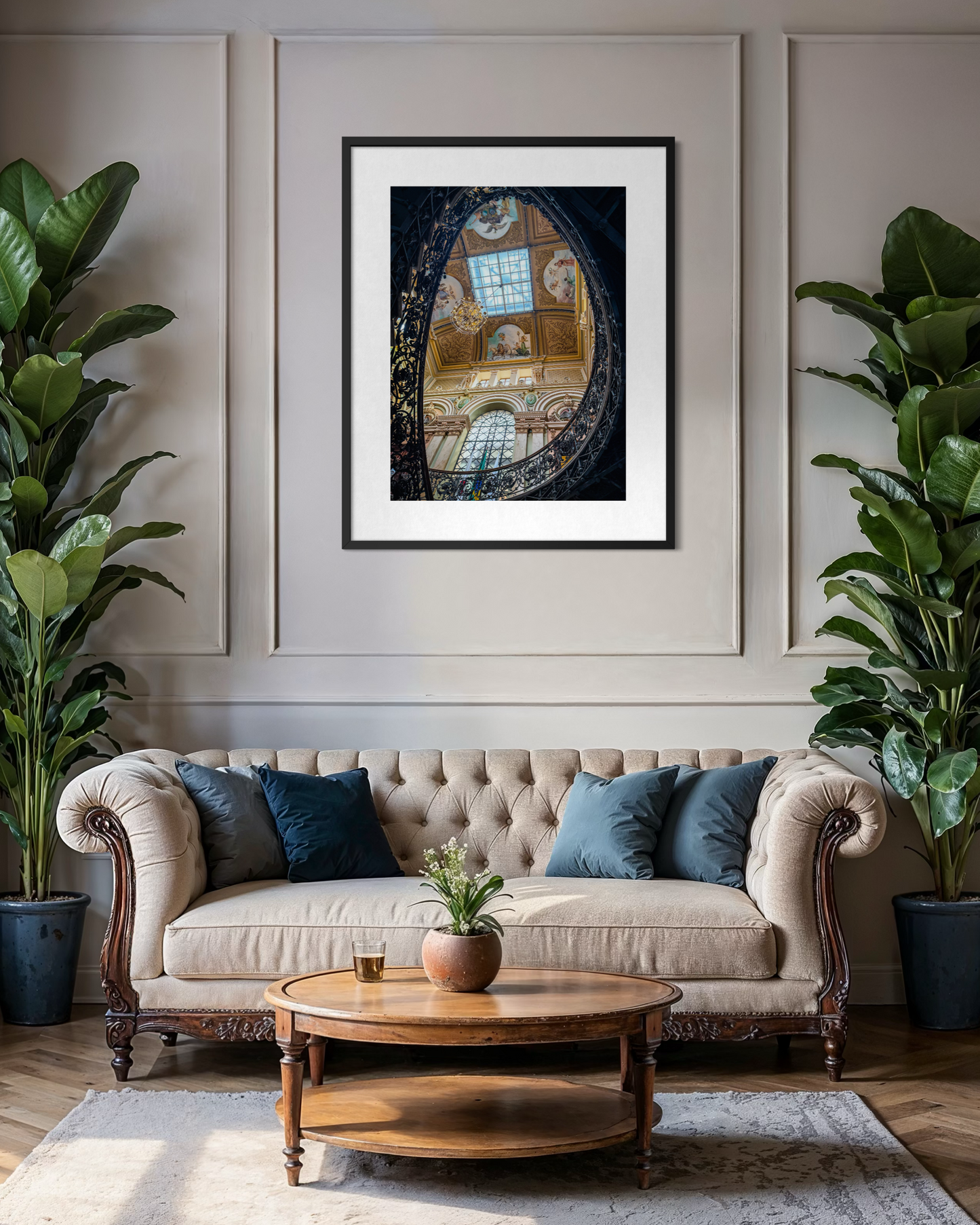 Elegant living room featuring a tufted beige sofa, lush green plants, a round wooden coffee table, and "Opulent Elegance Under the Skylight" fine art print by Leslie Brashear Photography inspired by the Palácio da Liberdade.