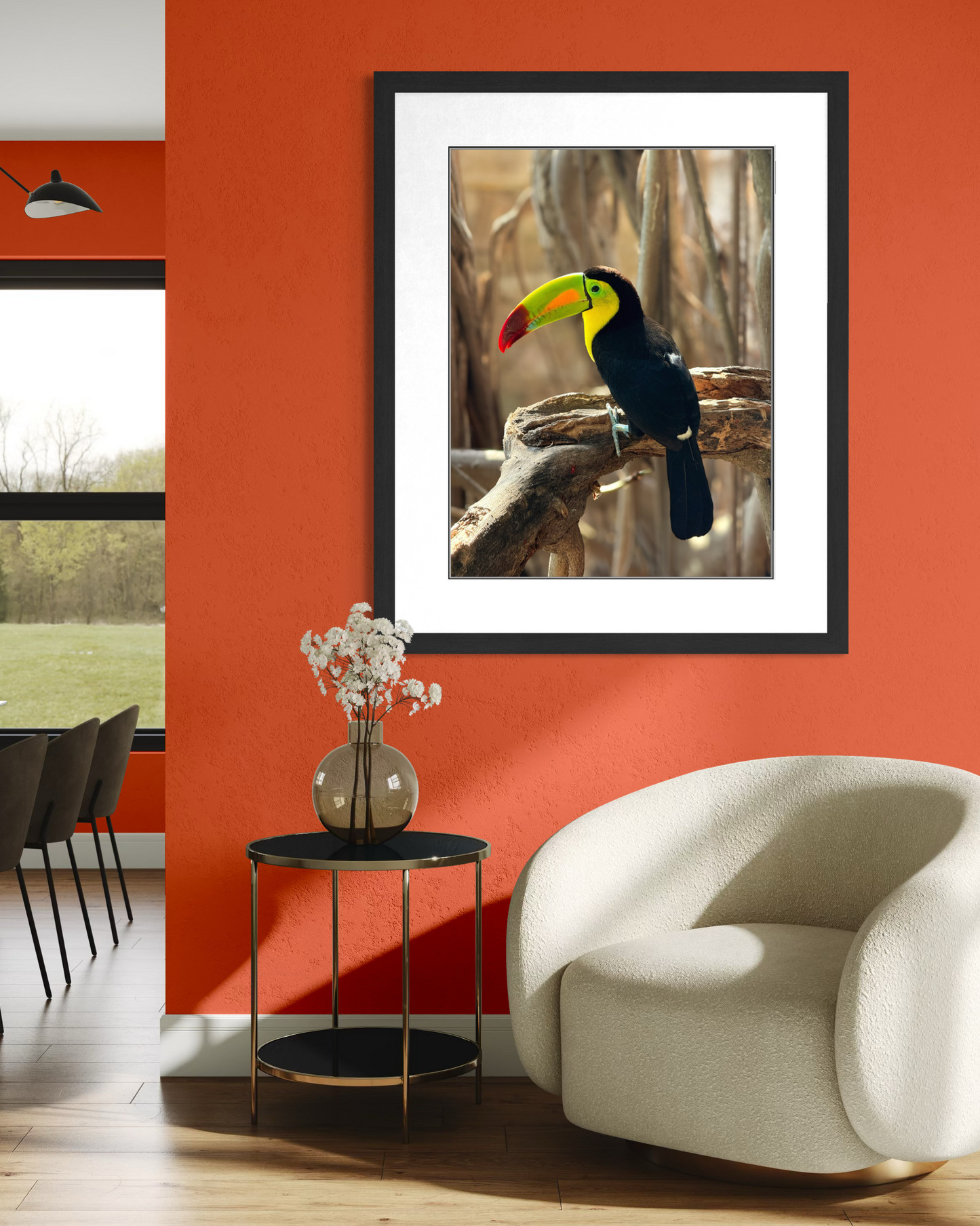 The "Vibrant Toucan Perched on Branch" by Leslie Brashear Photography hangs on an orange wall above a table with a vase, next to a white armchair, adding tropical flair to this modern living room.