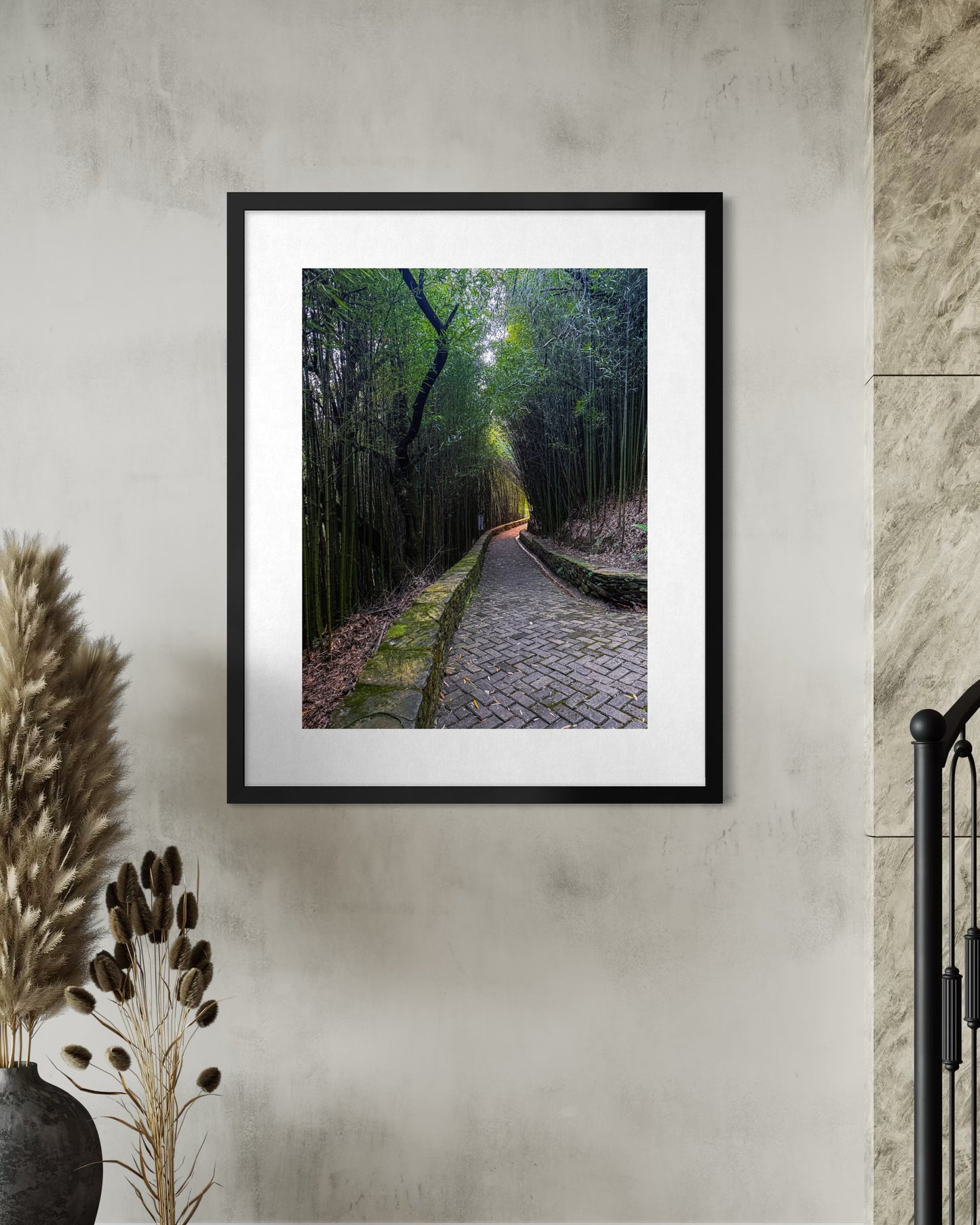 The "Enchanted Path Through Bamboo" fine art print by Leslie Brashear Photography hangs above dried plants, depicting the tranquil beauty of a serene Brazilian park with a lush bamboo canopy pathway.