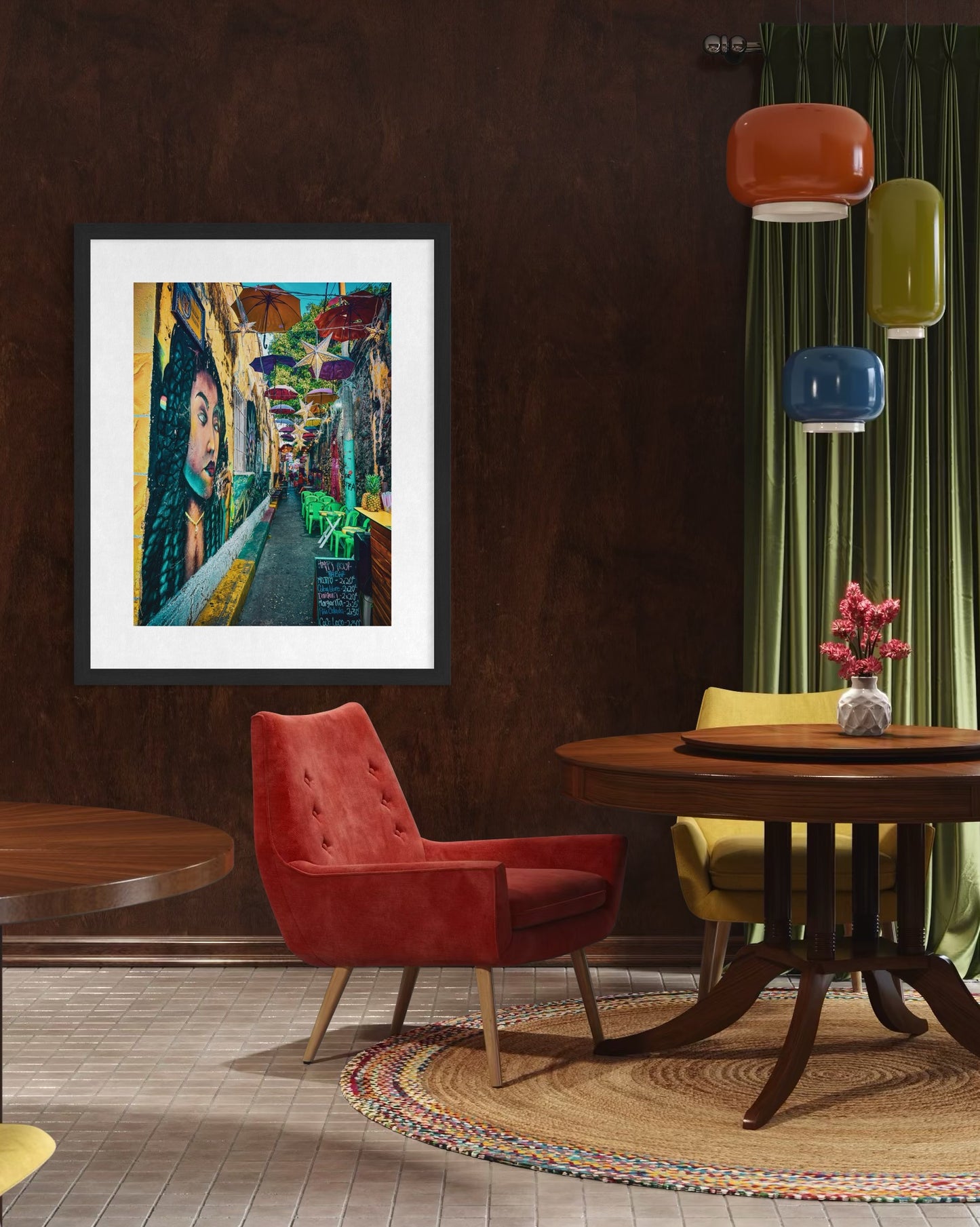 A modern dining area featuring round tables, colorful chairs, pendant lights, a green curtain, and "Getsemani Alley - Fine Art Print" by Leslie Brashear Photography showcasing Cartagena’s vibrant street scene.