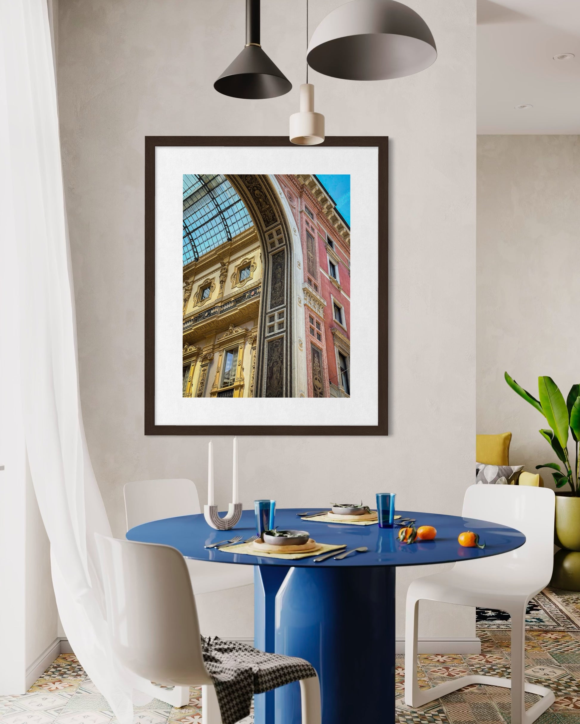 A modern dining area features a round blue table, white chairs, and "Ornate Architectural Detail at Galleria Vittorio Emanuele II" fine art print by Leslie Brashear Photography displayed above the table.