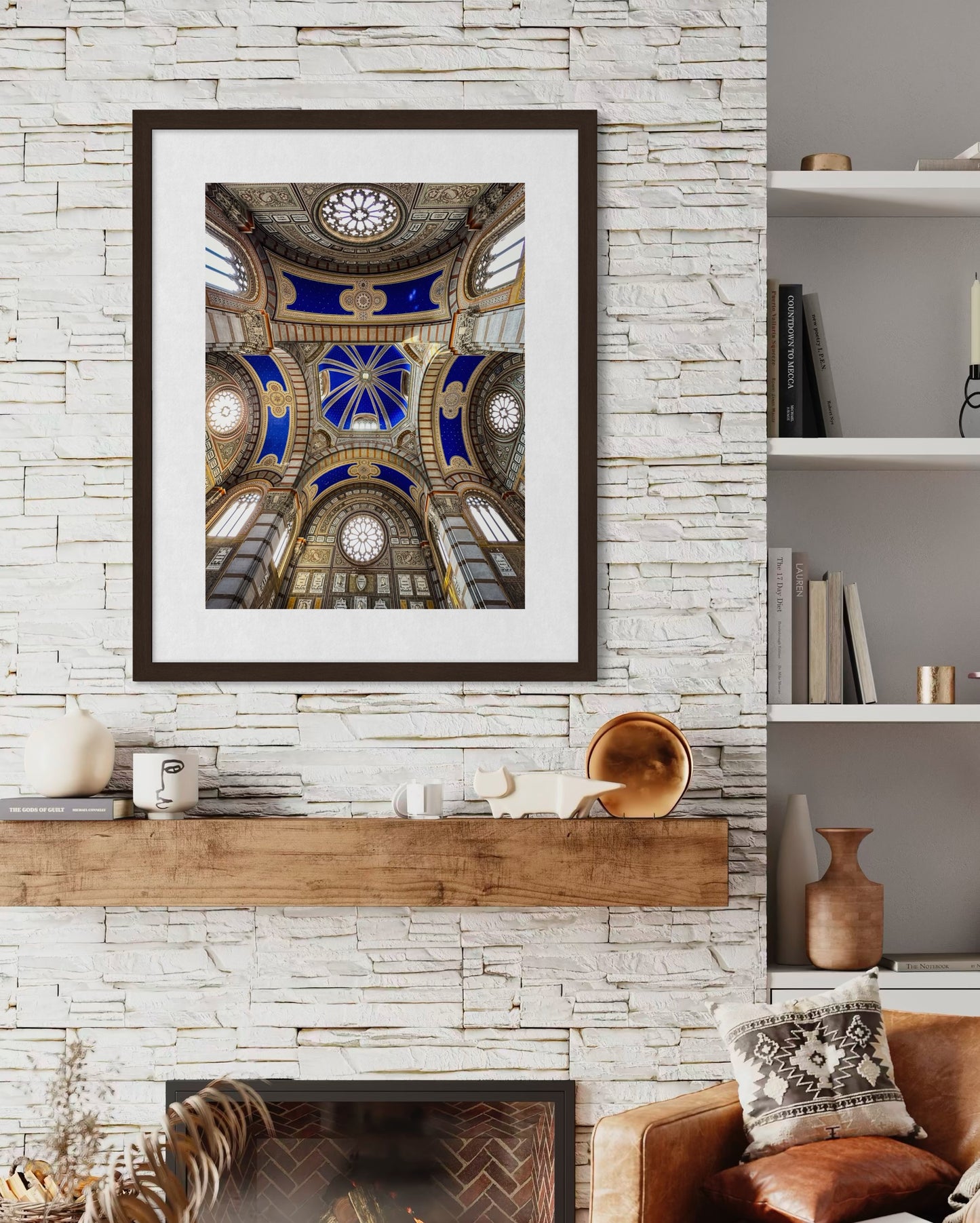 Leslie Brashear Photography's "Stunning Ceiling - Fine Art Print," featuring blue and gold Milan-inspired arches, is displayed above a wooden mantel on a white stone wall in a modern living room.
