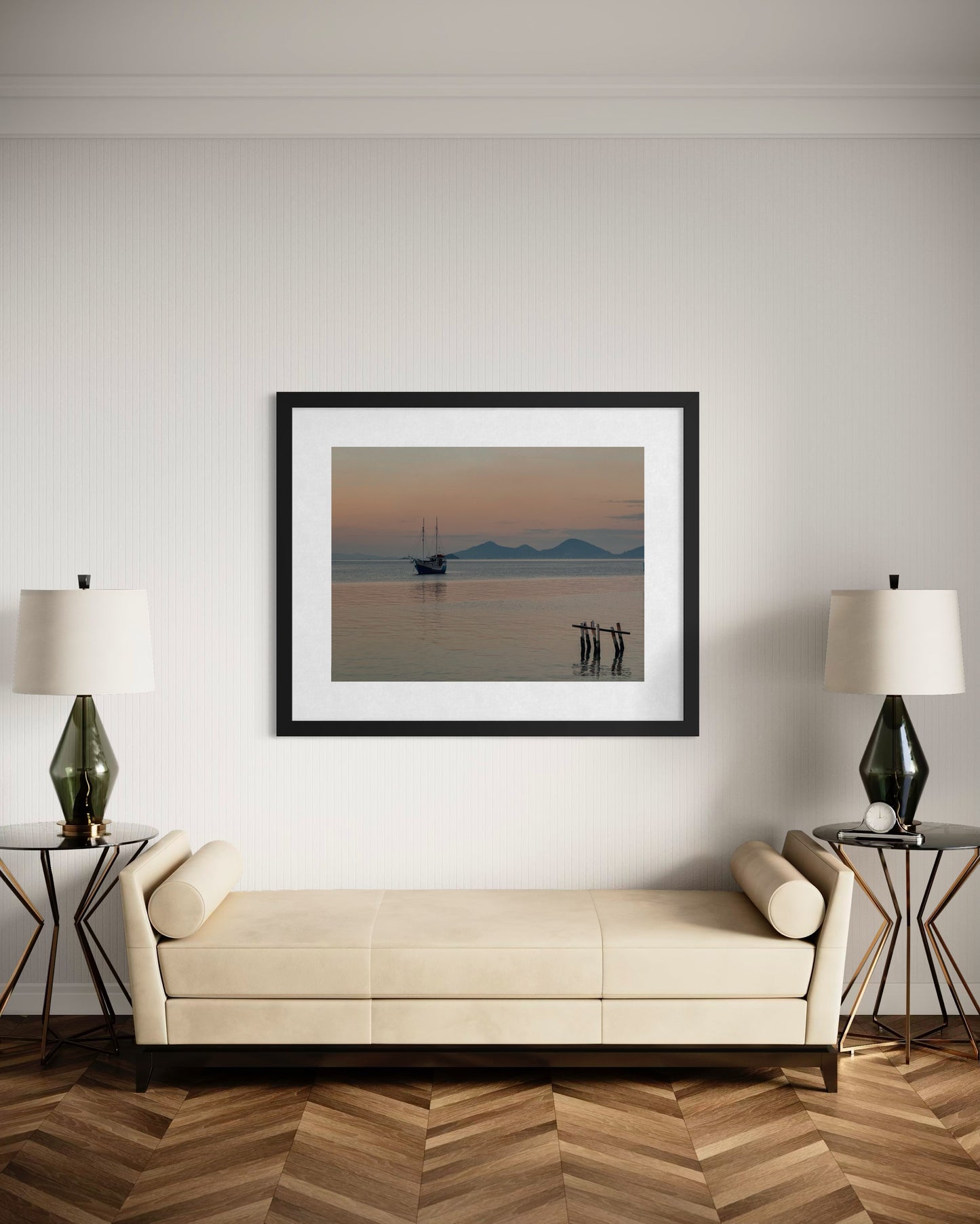 A minimalist living room features a cream sofa, two side tables with green lamps, and "Anchored in Tranquility - Fine Art Print" by Leslie Brashear Photography displayed above the sofa.