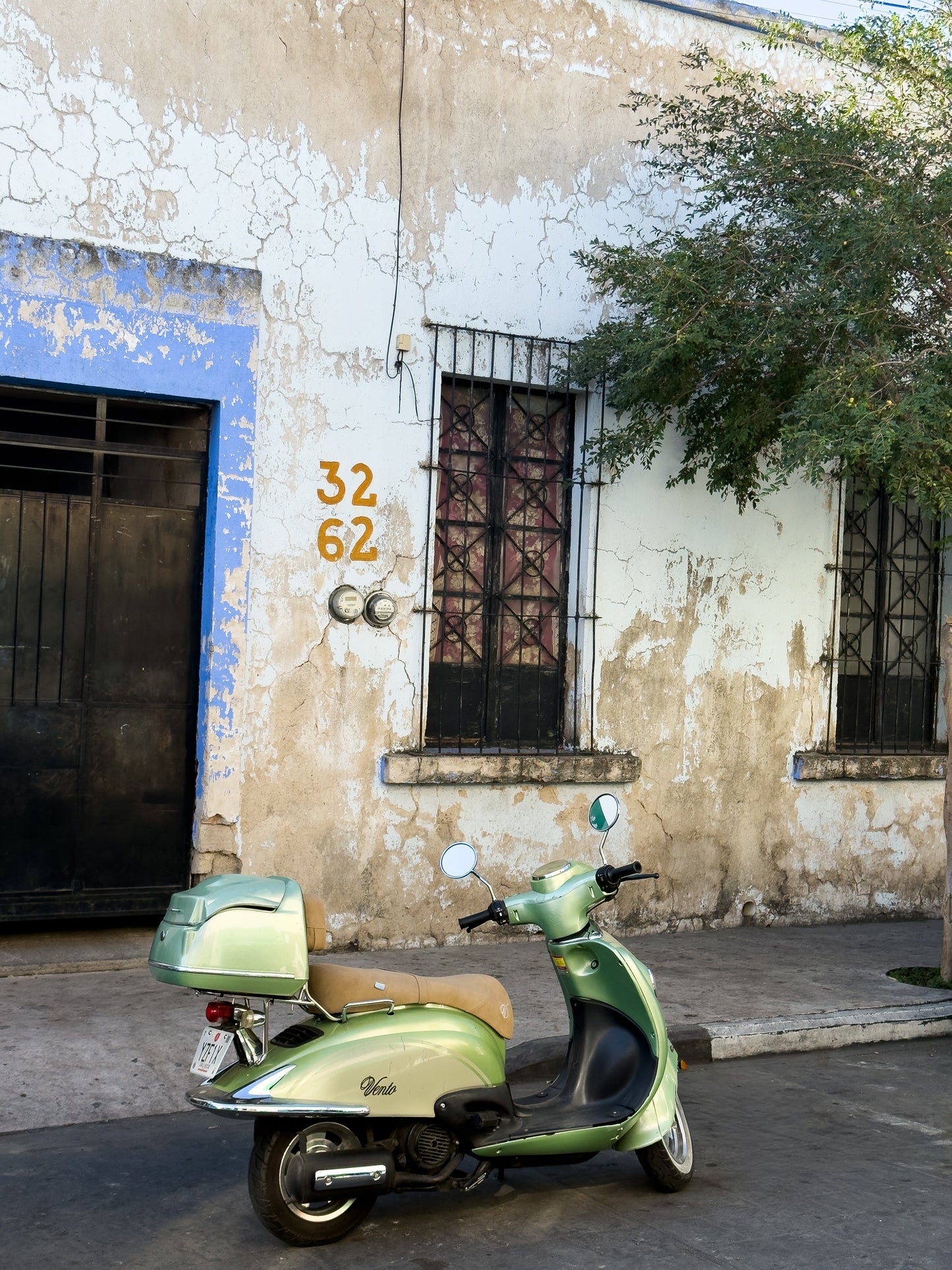The "Weathered Facade and Vintage Scooter - Fine Art Print" by Leslie Brashear Photography captures a pastel green scooter against an old, numbered building in Zapopan Jalisco, evoking a unique vintage vibe.