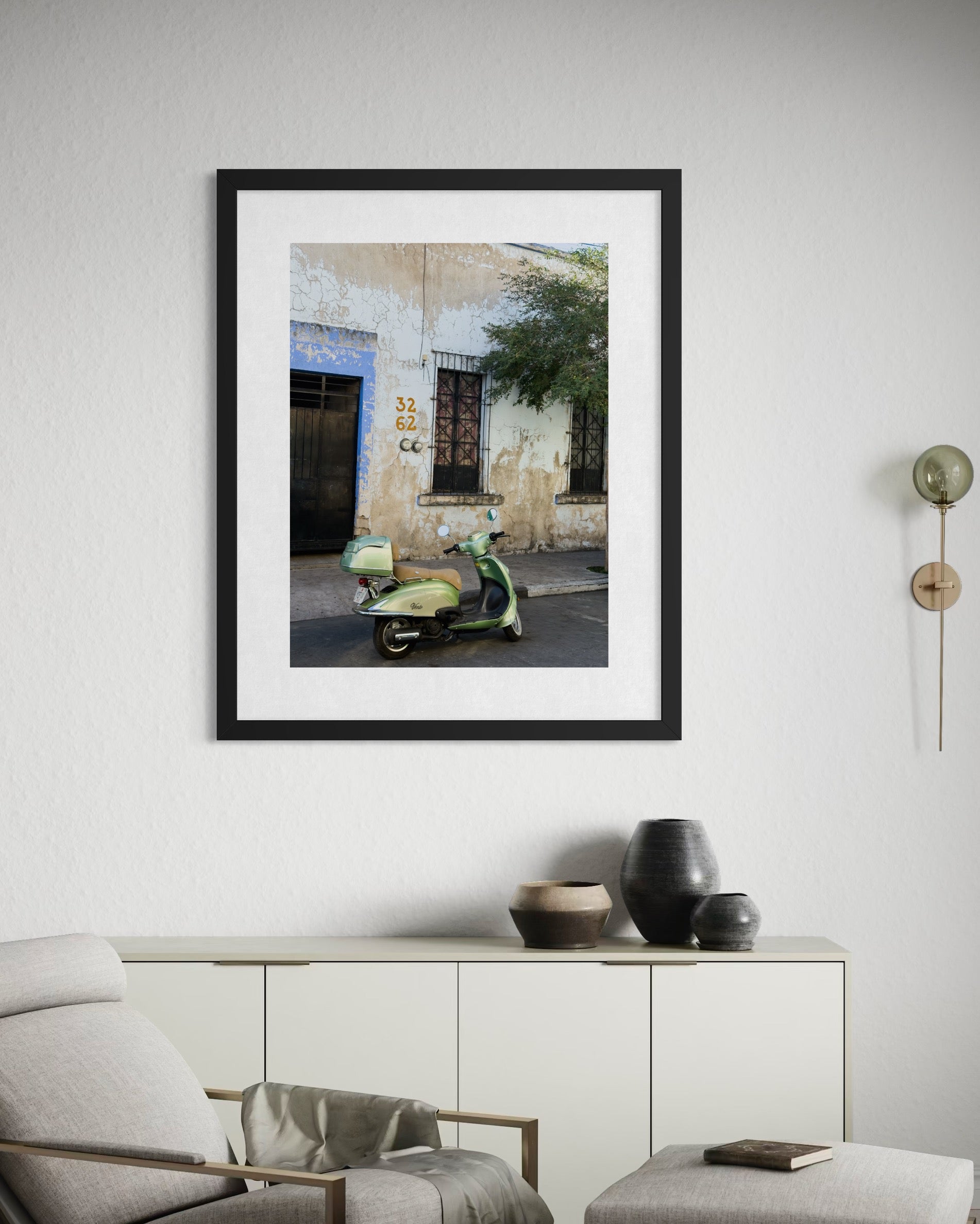 The "Weathered Facade and Vintage Scooter" fine art print by Leslie Brashear Photography adds vintage charm above a sideboard with decorative vases in a modern living room.