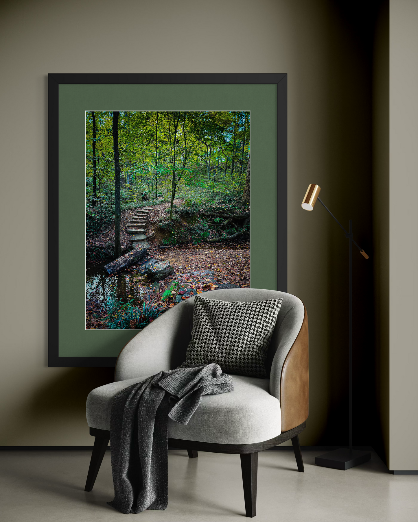 A modern chair with a cushion and gray throw sits before a wall showcasing "Stone Path," a large framed Deepdene Park forest photograph by Leslie Brashear Photography.