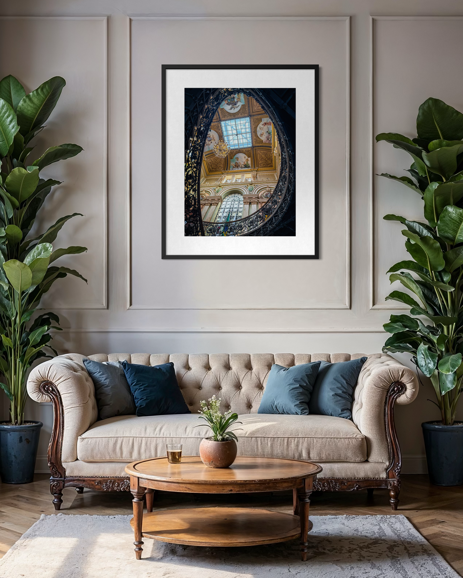 Elegant living room featuring a tufted beige sofa, lush green plants, a round wooden coffee table, and "Opulent Elegance Under the Skylight" fine art print by Leslie Brashear Photography inspired by the Palácio da Liberdade.