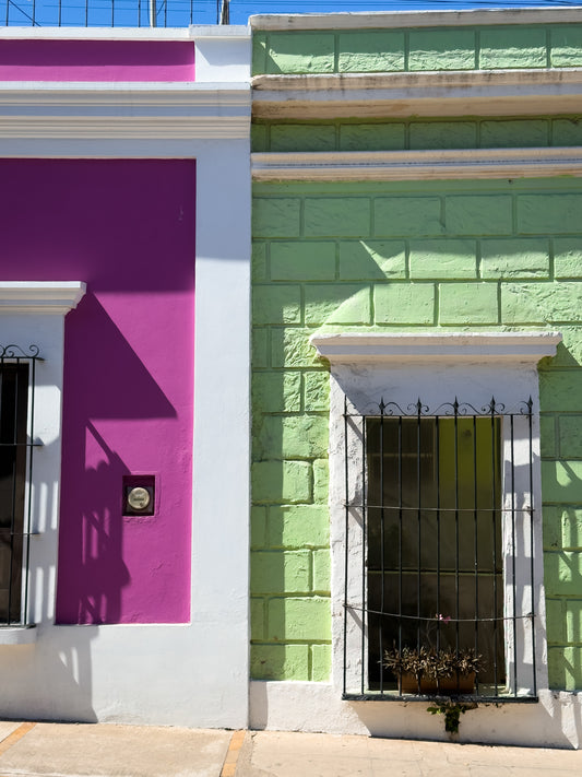 The "Magenta and Lime Facade" by Leslie Brashear Photography features a vibrant Mazatlán building with a magenta wall on the left, lime wall on the right, and windows adorned with black iron bars.