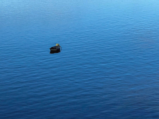 The "Serene Boat on Tranquil Waters - Fine Art Print" features a small black buoy with a yellow top floating alone on calm blue water, capturing the minimalist beauty of water photography.
