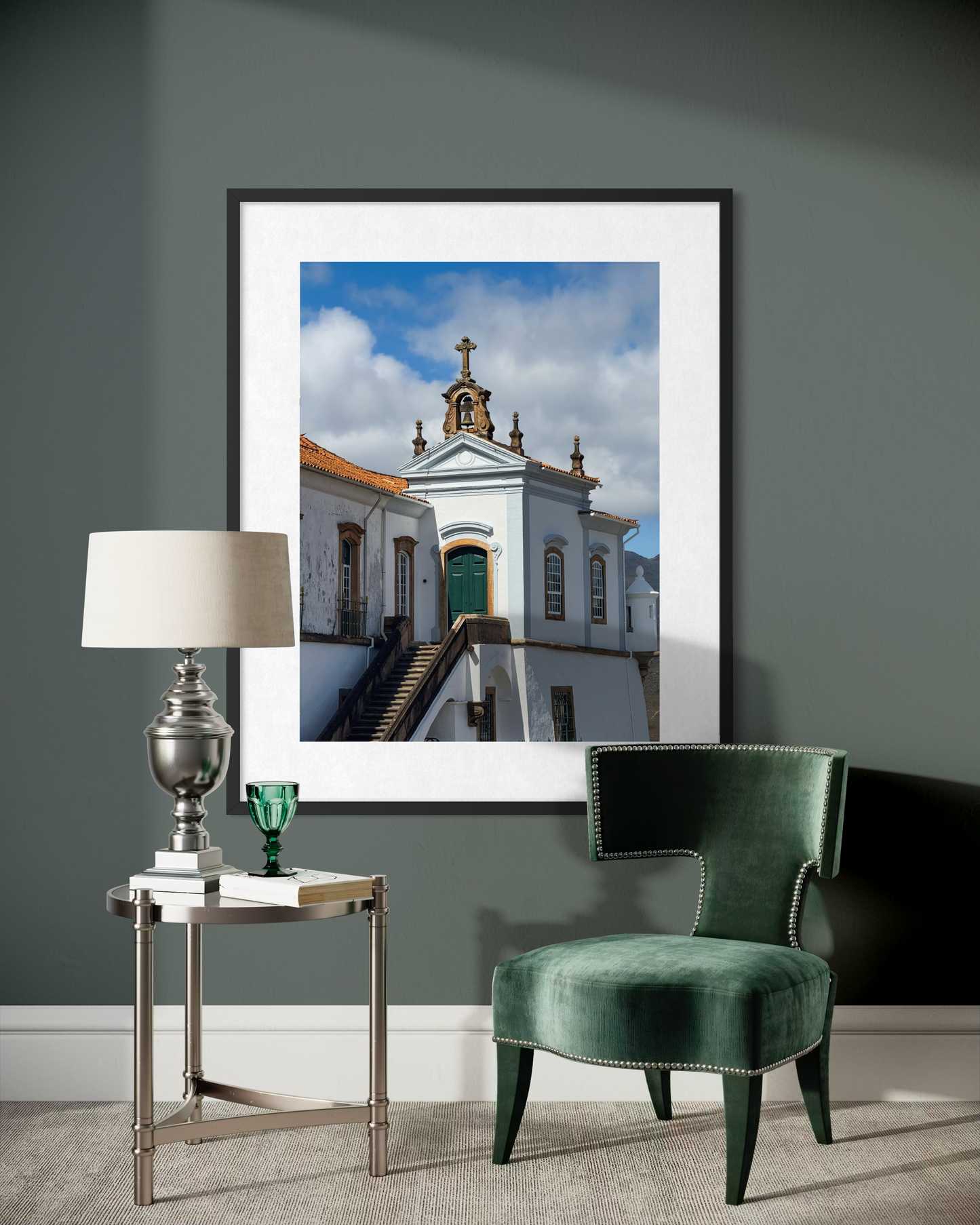 A modern living room features a green velvet chair, silver lamp on a side table, and "Historic Baroque Church in Ouro Preto" by Leslie Brashear Photography displayed on a dark gray wall.